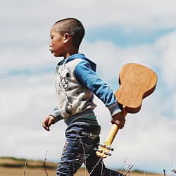 Boy Holding Ukulele and Walking